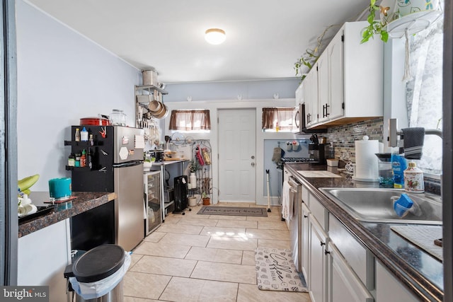 kitchen featuring appliances with stainless steel finishes, dark countertops, white cabinetry, and backsplash