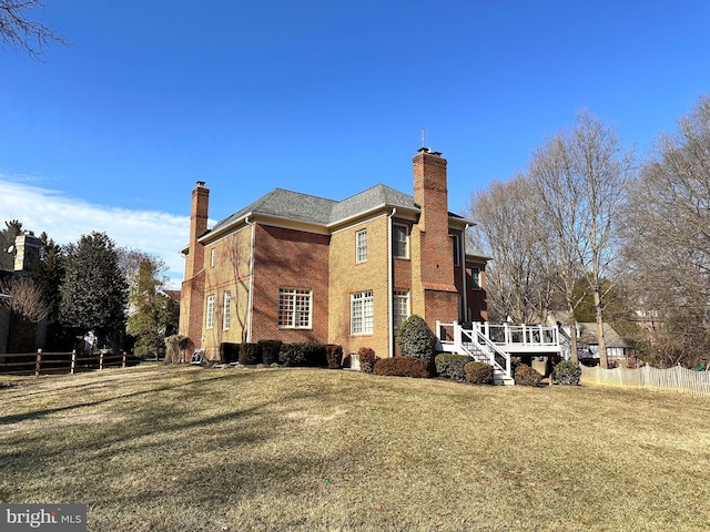 view of side of home with a chimney, fence, and a yard