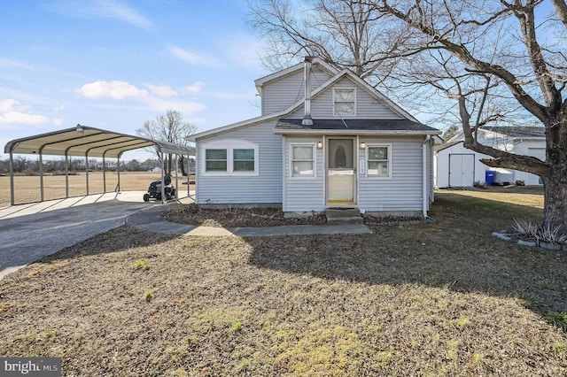 bungalow with an outbuilding, a storage unit, entry steps, a carport, and driveway