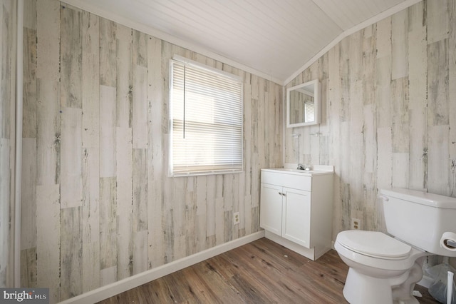 bathroom with lofted ceiling, toilet, wood finished floors, vanity, and baseboards