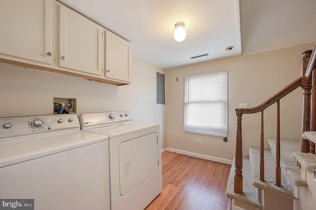 laundry area featuring cabinet space, electric panel, baseboards, light wood-type flooring, and separate washer and dryer