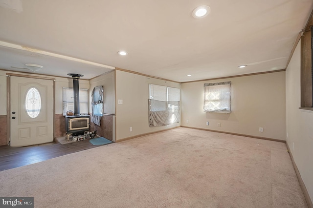 entryway featuring baseboards, carpet floors, a wood stove, and crown molding