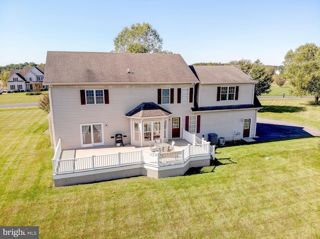 rear view of house with a yard, a deck, and a shingled roof