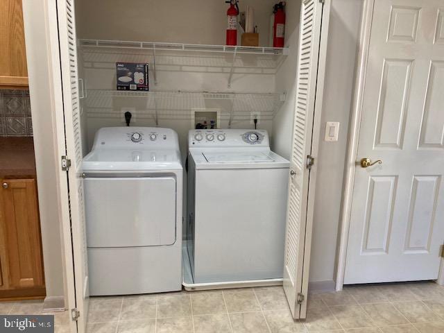 laundry area with laundry area, separate washer and dryer, and light tile patterned flooring