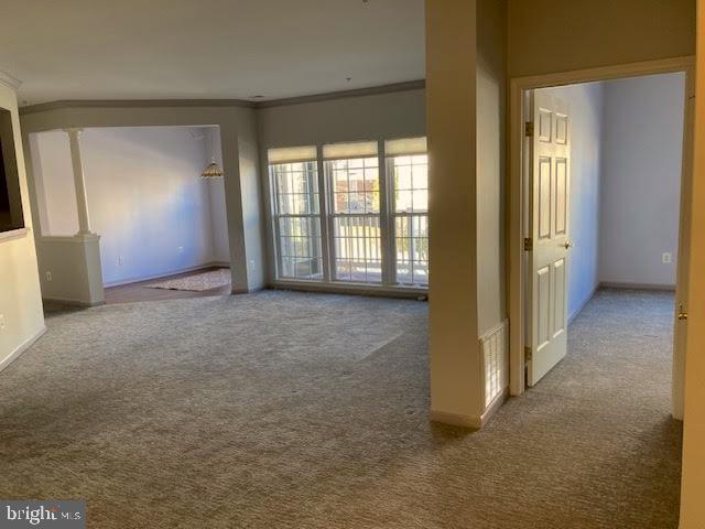 spare room with baseboards, visible vents, crown molding, carpet flooring, and ornate columns