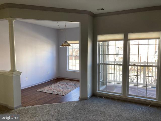 doorway to outside with decorative columns, visible vents, dark colored carpet, and crown molding