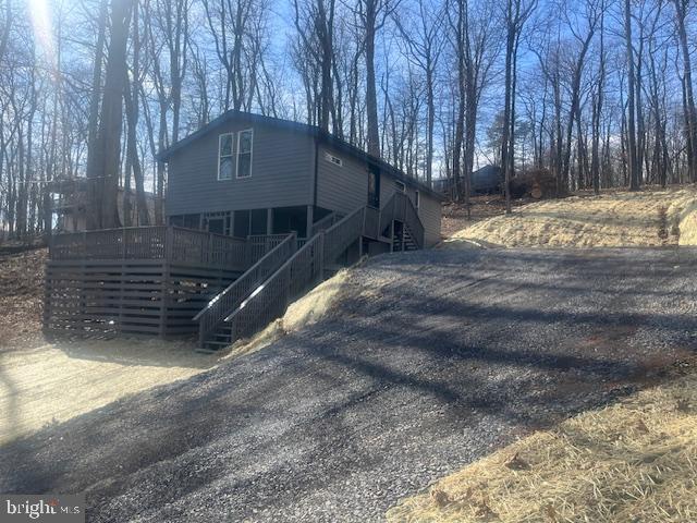 view of side of property with stairs, driveway, and a wooden deck