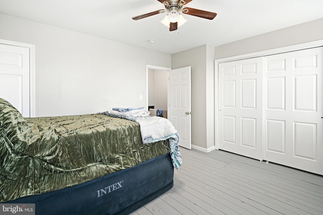 bedroom featuring ceiling fan, a closet, wood-type flooring, and baseboards