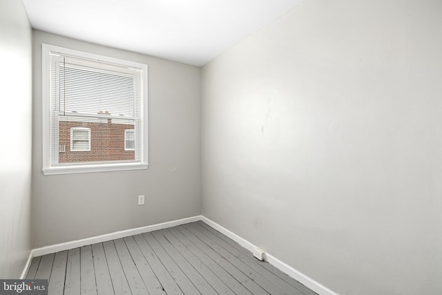 spare room featuring baseboards and hardwood / wood-style flooring