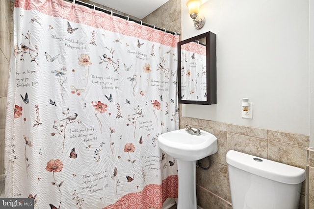 full bathroom featuring a shower with shower curtain, tile walls, and toilet