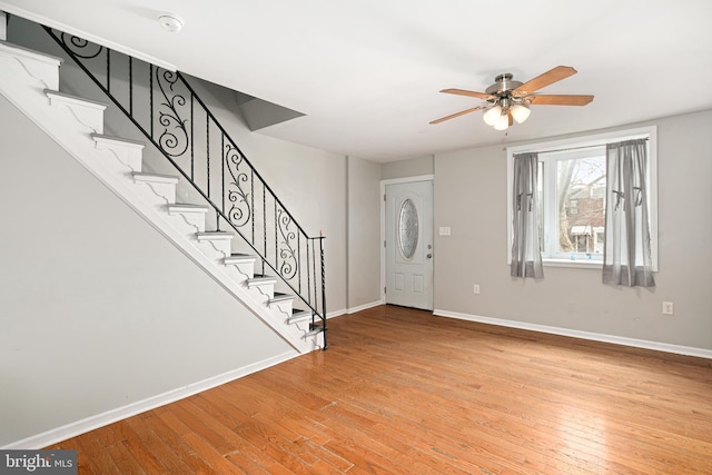 entryway featuring ceiling fan, stairway, light wood-style flooring, and baseboards