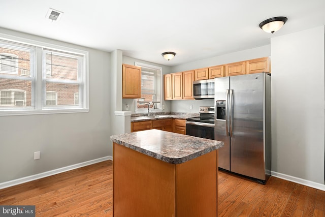 kitchen featuring stainless steel appliances, a wealth of natural light, visible vents, a sink, and wood finished floors