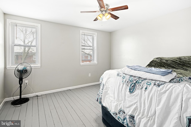 bedroom with ceiling fan, wood-type flooring, and baseboards