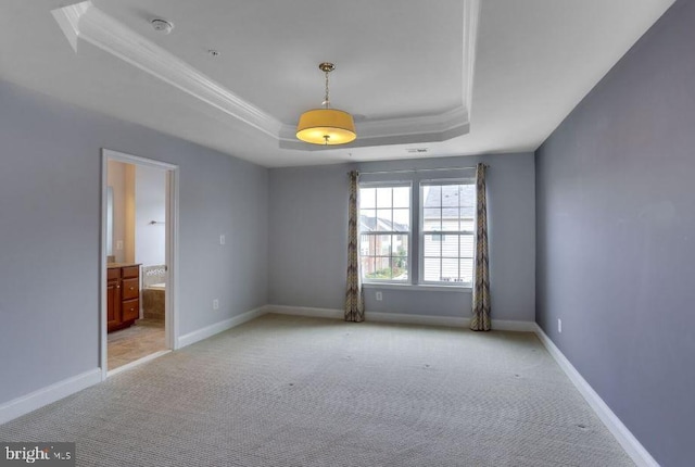 unfurnished room featuring a tray ceiling, light colored carpet, crown molding, and baseboards