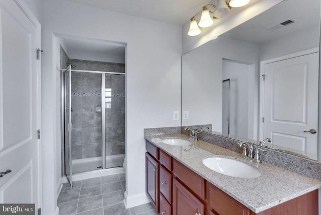 bathroom featuring tile patterned flooring, a shower stall, visible vents, and a sink