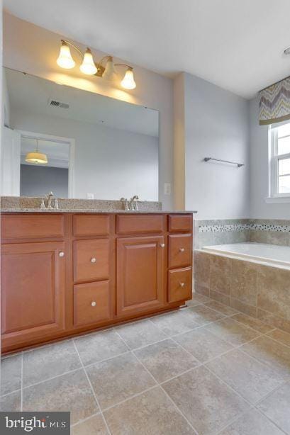 bathroom featuring tile patterned flooring, double vanity, a sink, and a bath