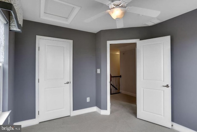 unfurnished bedroom with light carpet, attic access, visible vents, baseboards, and ceiling fan