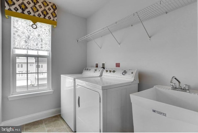 clothes washing area featuring washer and clothes dryer, light tile patterned flooring, a sink, laundry area, and baseboards