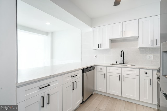 kitchen with light stone counters, white cabinets, backsplash, and stainless steel dishwasher