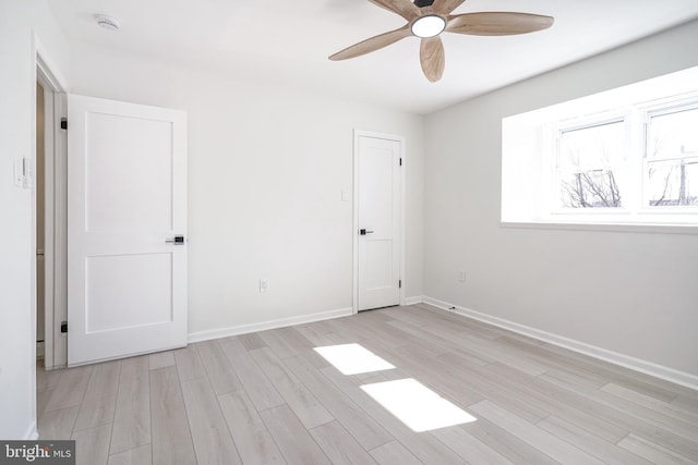 spare room featuring light wood-style floors, ceiling fan, and baseboards