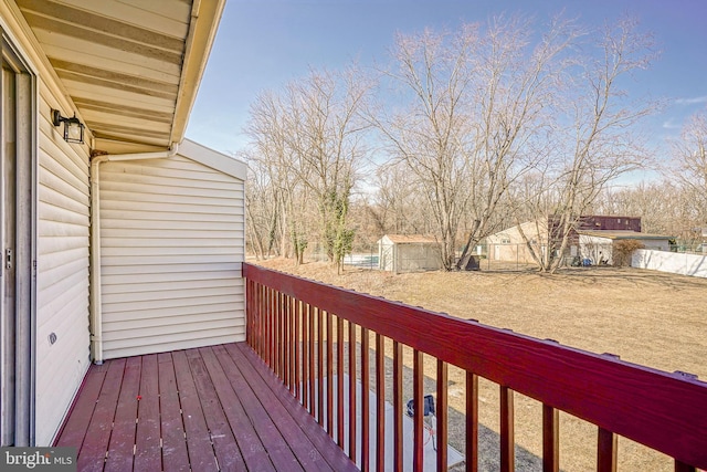 deck with a storage shed, fence, and an outdoor structure