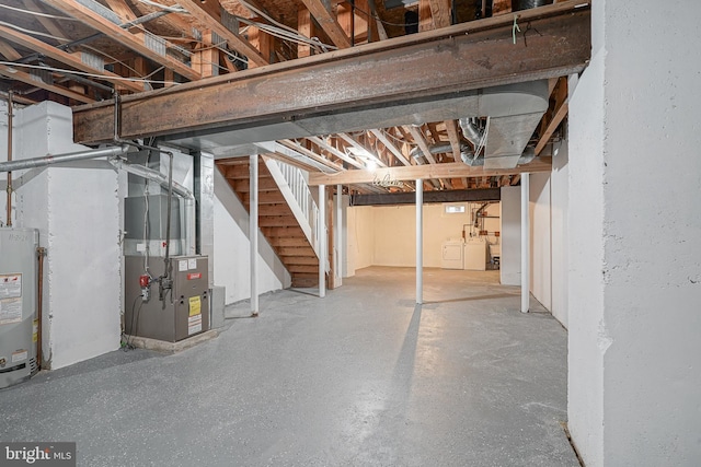 unfinished below grade area featuring gas water heater, washing machine and clothes dryer, heating unit, and stairs