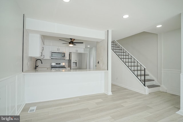 kitchen featuring appliances with stainless steel finishes, white cabinets, light countertops, and a peninsula