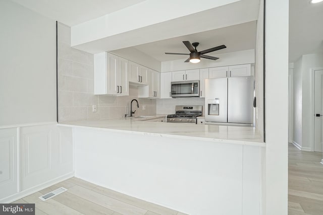 kitchen with a peninsula, visible vents, appliances with stainless steel finishes, and white cabinets