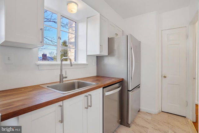 kitchen featuring a sink, white cabinetry, wooden counters, and stainless steel dishwasher