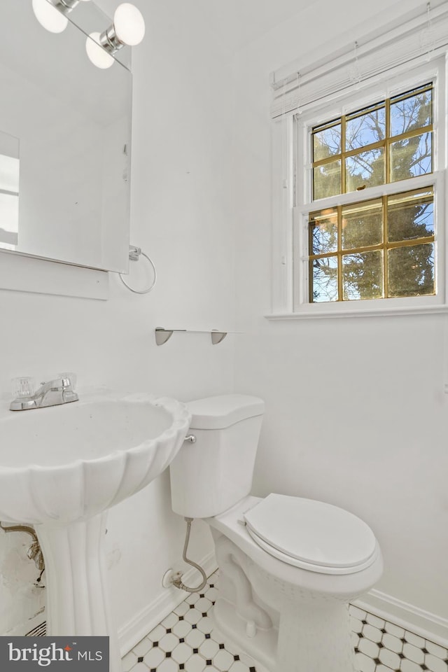 half bath featuring baseboards, toilet, and tile patterned floors