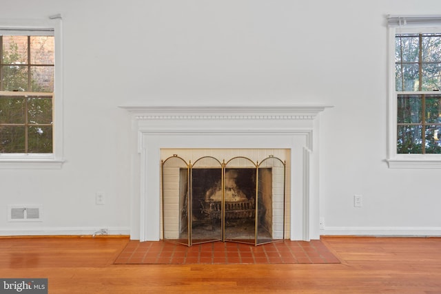 details with a fireplace with flush hearth, visible vents, and wood finished floors