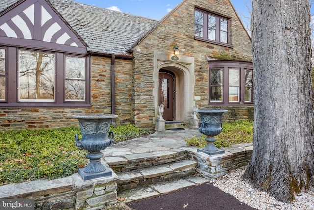 property entrance with a high end roof and stone siding