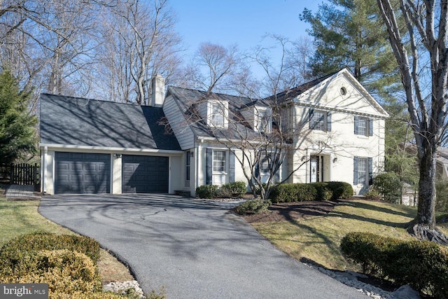 view of front of home with an attached garage, driveway, a chimney, and stucco siding