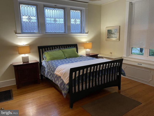 bedroom featuring visible vents, baseboards, and wood finished floors