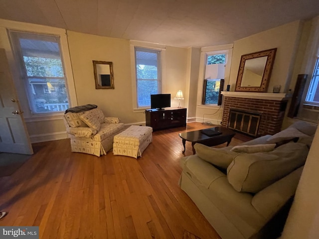 living area featuring plenty of natural light, a fireplace, baseboards, and wood finished floors