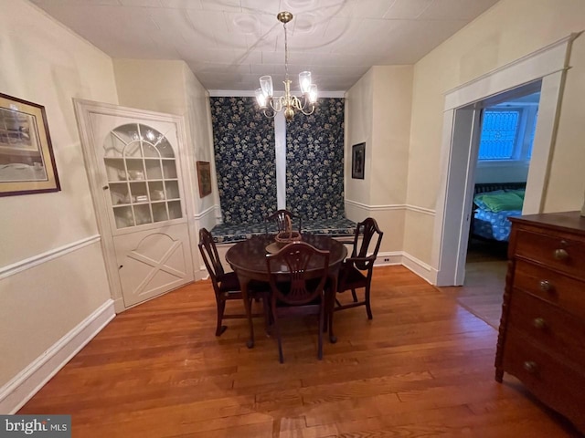 dining room featuring baseboards, wood finished floors, and an inviting chandelier