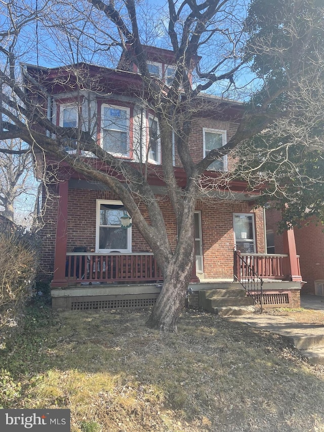 view of front of property featuring covered porch, a front yard, and brick siding