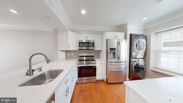 130 Saint Charles Sq Unit 130, Sterling, VA 20164 - kitchen with white cabinets, a sink, appliances with stainless steel finishes, stacked washing maching and dryer, and light stone countertops