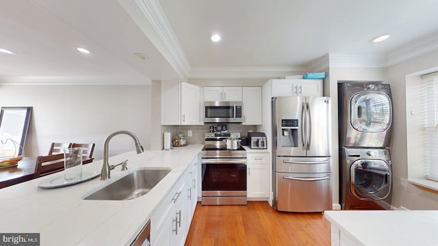 130 Saint Charles Sq Unit 130, Sterling, VA 20164 - kitchen with stacked washer / drying machine, light stone countertops, a sink, stainless steel appliances, and white cabinetry