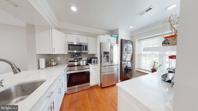 130 Saint Charles Sq Unit 130, Sterling, VA 20164 - kitchen with a sink, stacked washer and clothes dryer, visible vents, light wood-style flooring, and appliances with stainless steel finishes