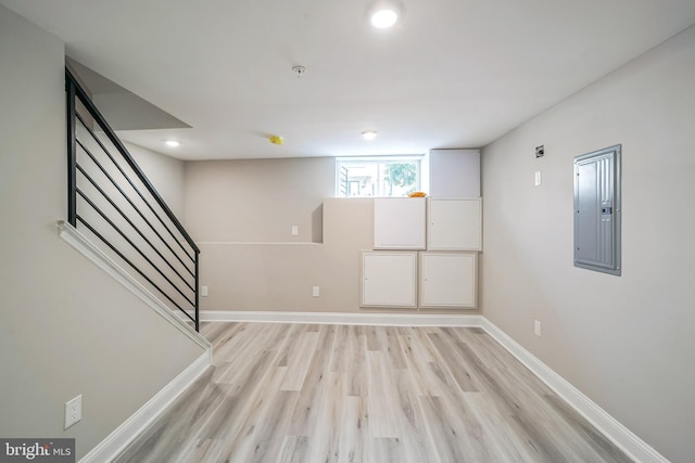 below grade area with recessed lighting, baseboards, stairs, electric panel, and light wood finished floors