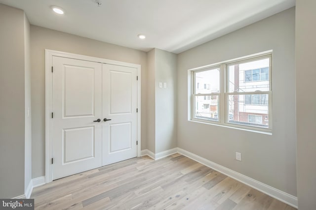 unfurnished bedroom featuring a closet, light wood-style flooring, and baseboards