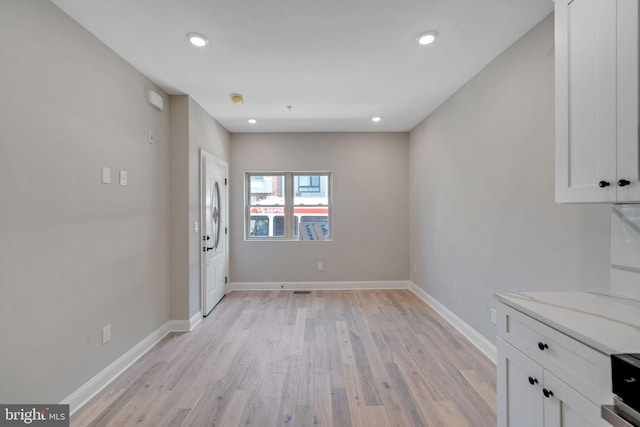 unfurnished dining area with light wood finished floors, baseboards, and recessed lighting