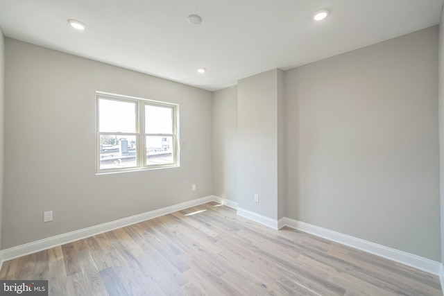 spare room featuring light wood finished floors, recessed lighting, and baseboards