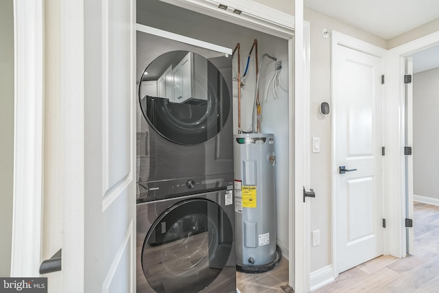 laundry room with light wood finished floors, water heater, stacked washing maching and dryer, laundry area, and baseboards