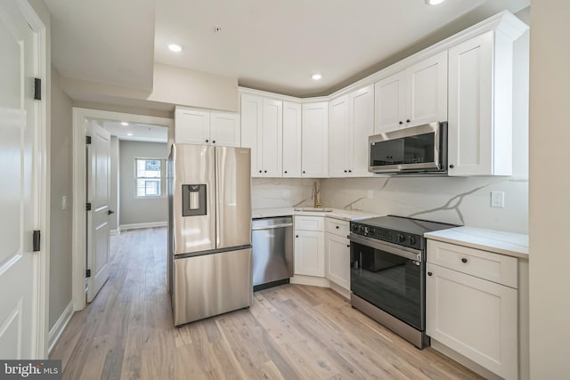 kitchen featuring recessed lighting, white cabinets, appliances with stainless steel finishes, light wood-type flooring, and backsplash