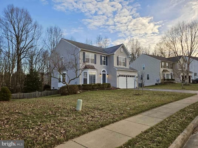 view of front of property featuring an attached garage, fence, and a front lawn