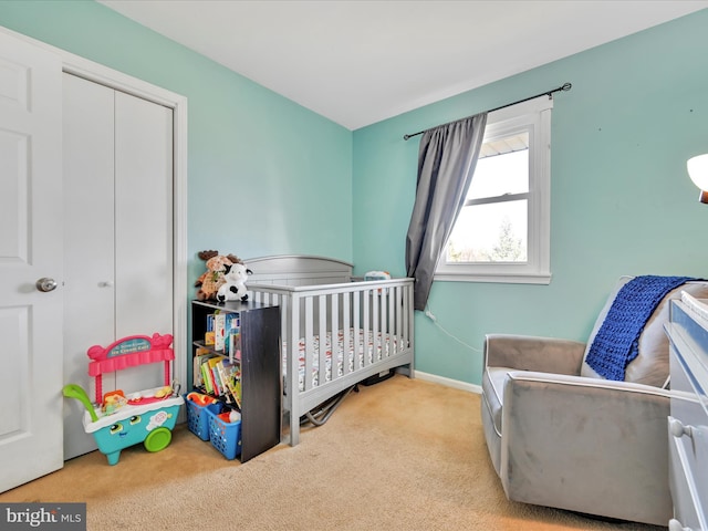 bedroom with a closet, a nursery area, baseboards, and carpet