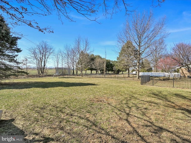 view of yard with a trampoline and fence