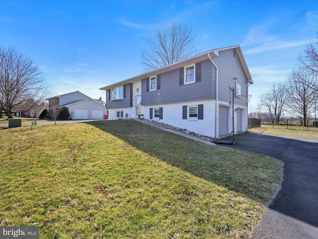 split foyer home with a garage, a front lawn, driveway, and fence